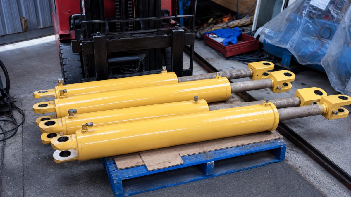 Reconditioned hydraulic cylinders, freshly painted and stacked on a pallet ready for refitting.